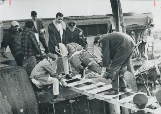 Injured engineer of the wrecked train, Stewart Vince, is carried on a stretcher over a makeshift ramp