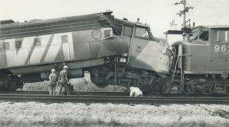 CN repairmen examine the crumpled front of a VIA Rail locomotive that smashed into a stopped freight train near Ingersoll yesterday. More than 70 pass(...)