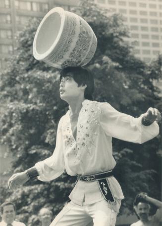 Acrobat urns his living. Eve and Frank Harder of Winnipeg (right) were part of a lunchtime crowd at Nathan Phillips Square yesterday for a show by the(...)