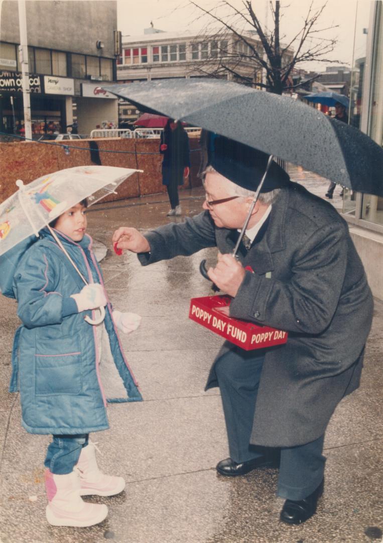 Keeping the memory alive. Under umbrellas outside the Eaton Centre yesterday, Crystal Burk, 6, purchases a poppy from Walter Dmytrenko, 65, a member o(...)