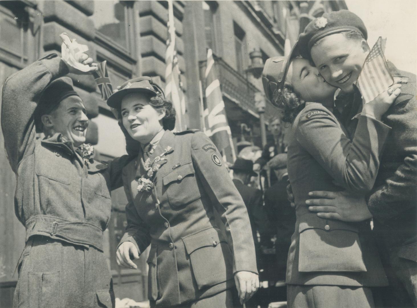 Amid all the joyous scenes of revelry accompanying London's long-awaited announcement of victory, a Canadian soldier, gets his V-Day kiss from a C.W.A.C. sweet-heart