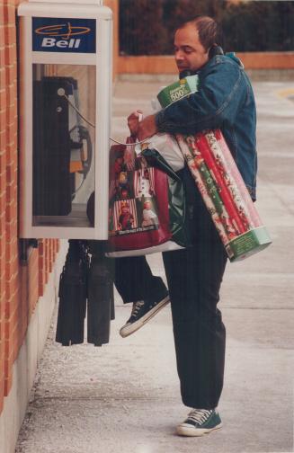 Bearing gifts: Loaded down with late Christmas purchases, Vince Diano tries to call a cab yesterday from Yorkdale Shopping Centre