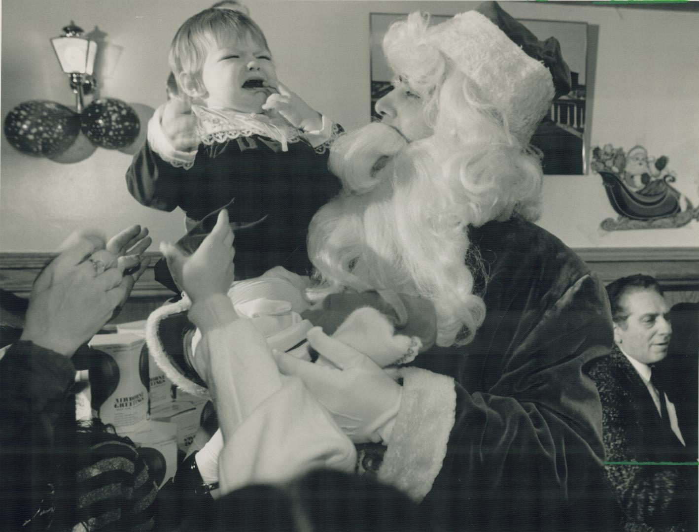 Just cut the small talk: 17-month-old Naomi Greeman is less than delighted to meet Santa Claus yesterday at a free Christmas party for 600 hosted by caterer Joe Garisto