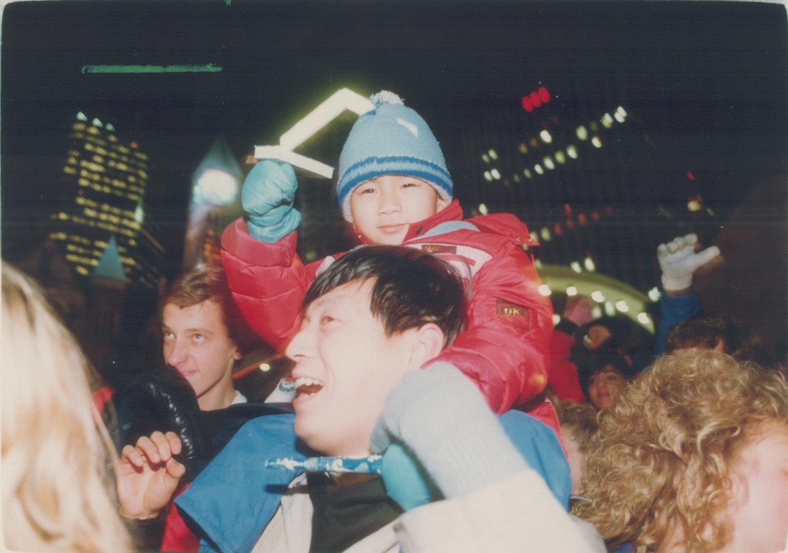 Above it all: Four-year-old Kawal Lam -- perched on his father Sluping's shoulers -- greets the new year at midnight at Nathan Phillips Square