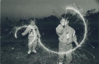 Sparkling Effort: Elyse McKeown, 3, left, and Kyle Glasson, 4, trace dazzling designs in the air with sparklers during last night's Victoria Day celebrations at Woodbine beach