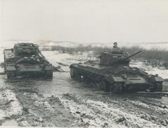 Plowing through mud and water Valentines are given a final taste of the weather they may expect on the Russian fronts next winter. Capt. Sokolov's ver(...)