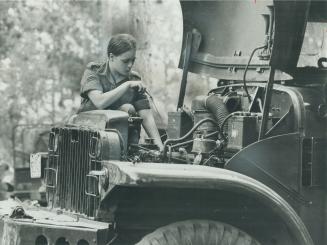 Peggy Havrileska checks dipstick of army truck