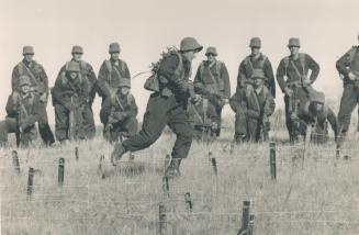 Clearing obstacles: Pte. Pasqualina Petruzzi runs through the barbed wire infiltration exercise. Meanwhile, right, Marie Larivee swings through an obstacle course