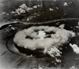 Brighter than the sun. A mushroom-topped column of smoke and gas, brighter than the sun, rises through a disintegrating vapor cloud over Bikini Lagoon(...)