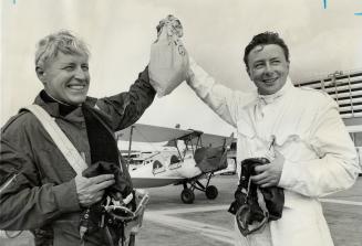 Holding aloft mail they flew to Malton from Montreal in Tiger Moth biplane in background are Thomas R