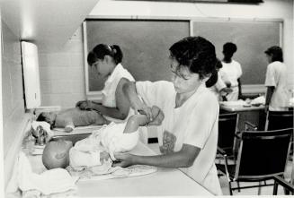 Danica Pierce, right, and Lynne Campbell, both 12, learn how to change a baby's diaper using dolls at a St