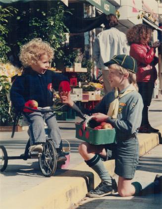 Tricyle-riding Remington, 3, buys an apple from Cub Christopher Jones, 9, in the Beaches during Scouts Canada Apple Day yesterday. The 10,000 Beavers,(...)