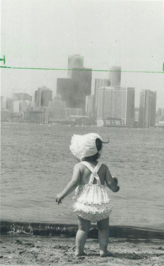 Wonderful wading weather. one-year-old Lindsay Tapscott pauses for a moment to view the downtown skyline from Toronto Island before dipping her toes i(...)