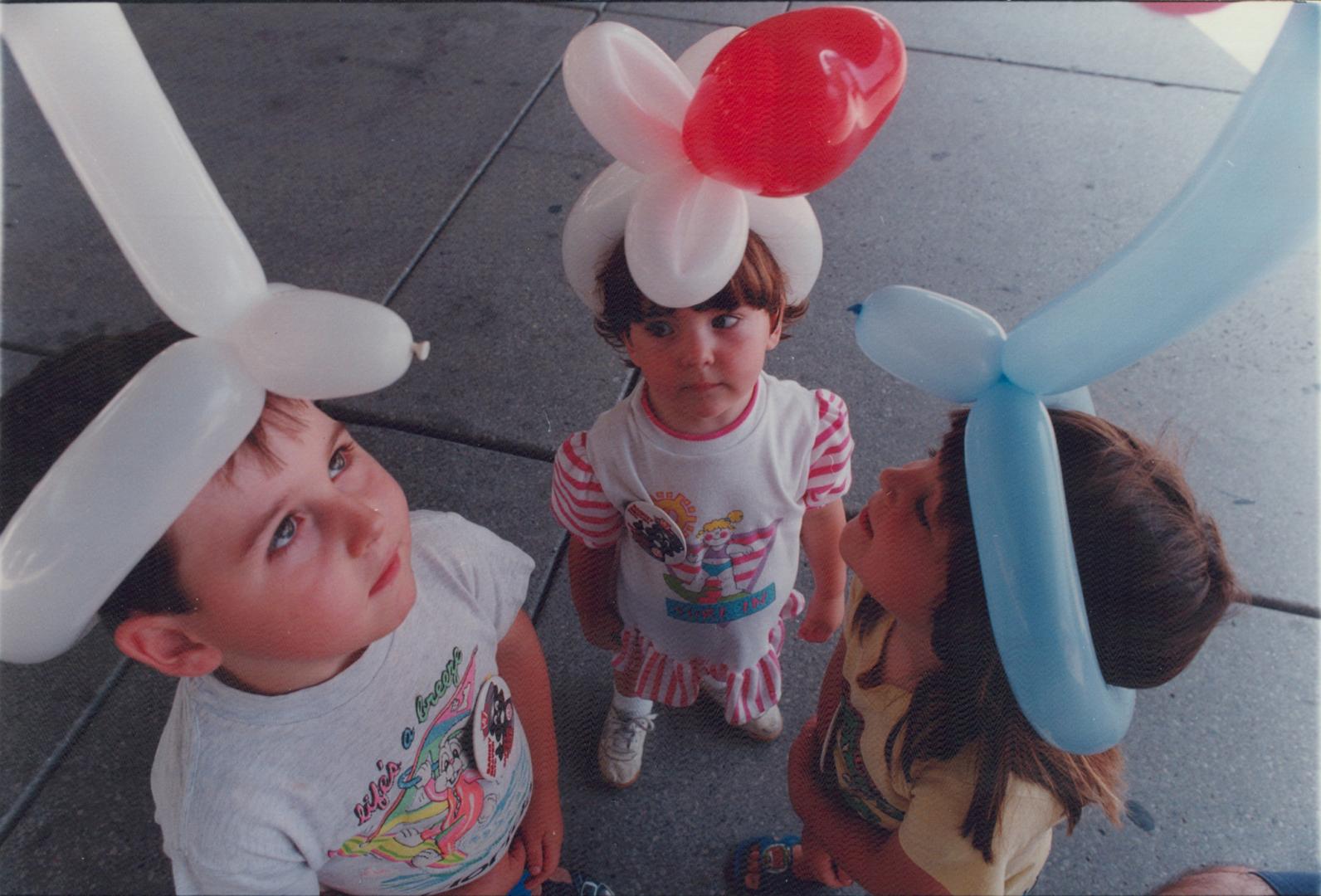 Balloon heads: Tyler Carmichael, 5, left, Telise Carmichael, 2, and Lisa Neumeyer, 4, compare hats last week at Kidsummer at Nathan Phillips Square