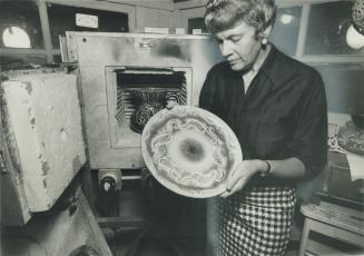 Artist's workroom where Bronka Michalowska produces all her work has a kiln where she fires the enamelled tile, jugs and bowls. Here she examines a pl(...)