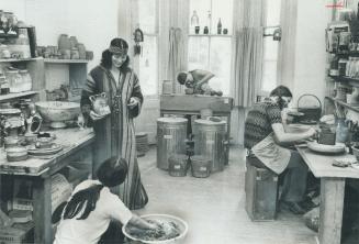 Pottery craftsman Bonita Collins (in headband and long gown) talks shop with student Bev Wagner