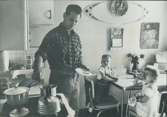 After day's work as carpenter, Bruno Laucys takes over job of caring for ronnie, 2, Diane, 4, while wife works night shift. Bruno, born in Lithuania, (...)