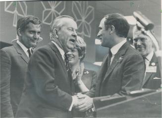 congratulating his successor, Prime Minister Pearson shakes the hand of newly-elected Liberal party leader Pierre Elliott Trudeau (right) on platform (...)