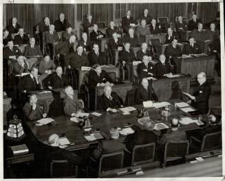 The nine provincial premiers, seated around the centre table, and their chief cabinet aides, hear Prime Minister King open the historic conference wit(...)