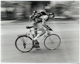 Downtown bike courier Bill Herdman tries a charcoal fitter face mask to relieve his burning lungs in yesterday's scorcher as he whizzes along King St. W. The masks sell in bike shops for about $10