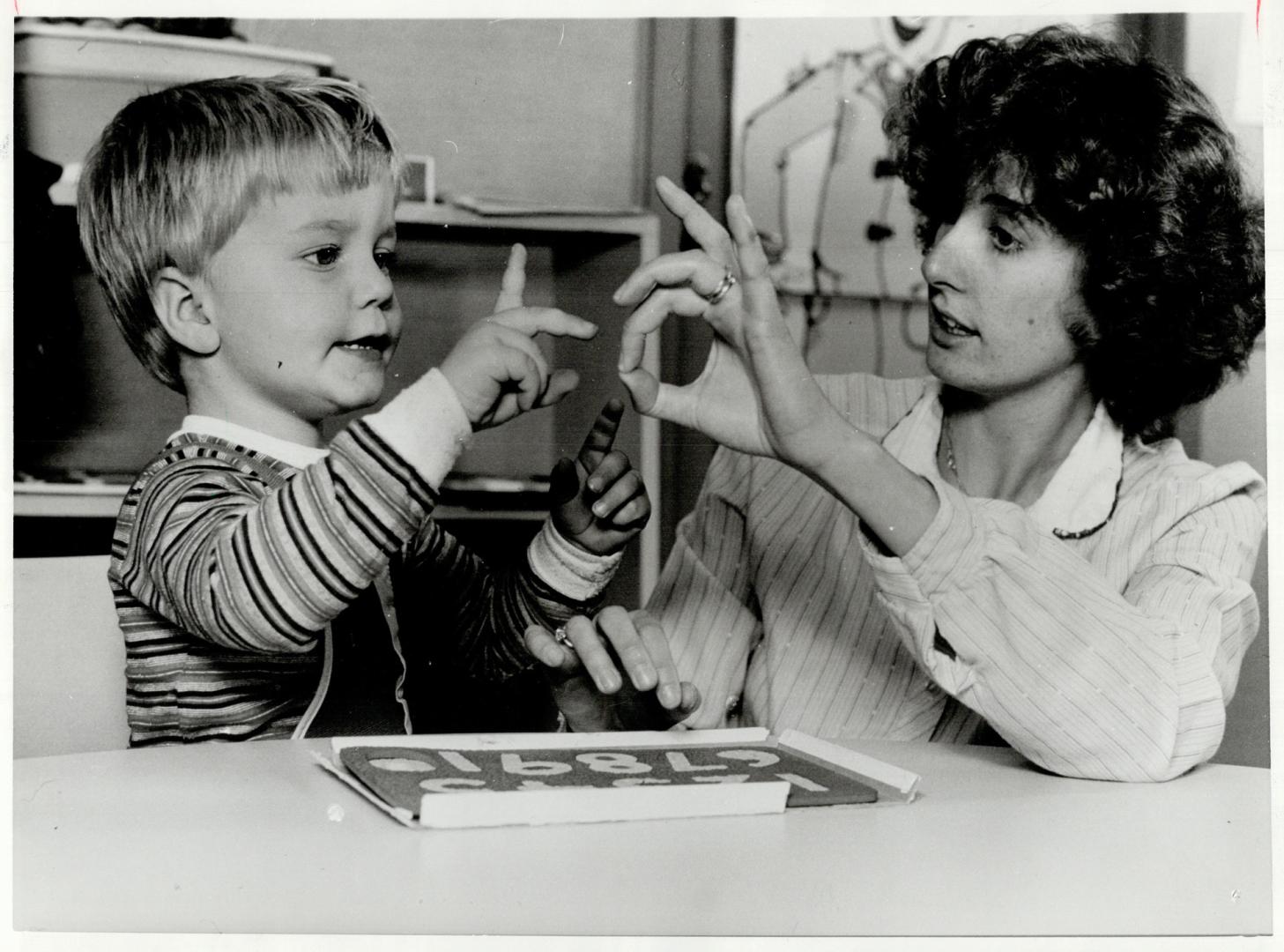 Kim Reid helps Jonathan Rorke, 3, sign numbers