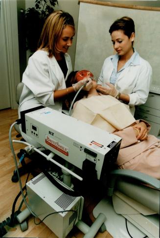 Grin and bare it: Laser technicians Andrea Radman, left, and Angela Liolios give patient Josie Buzzanca a whiter smile