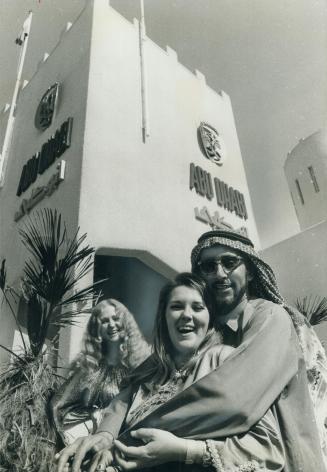 Two of the four Canadian girls working in the pavilion of the small sheikdom of Abu Dhabi pose with Arab deputy commissioner Abdulla Danwood. They're(...)