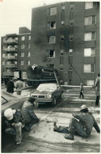 Stunned by Blast, workmen lie near tar tank which exploded yesterday, sending two men to hospital, Men had parked tanker behind Windermere Ave. apartment building to pump tar to roof