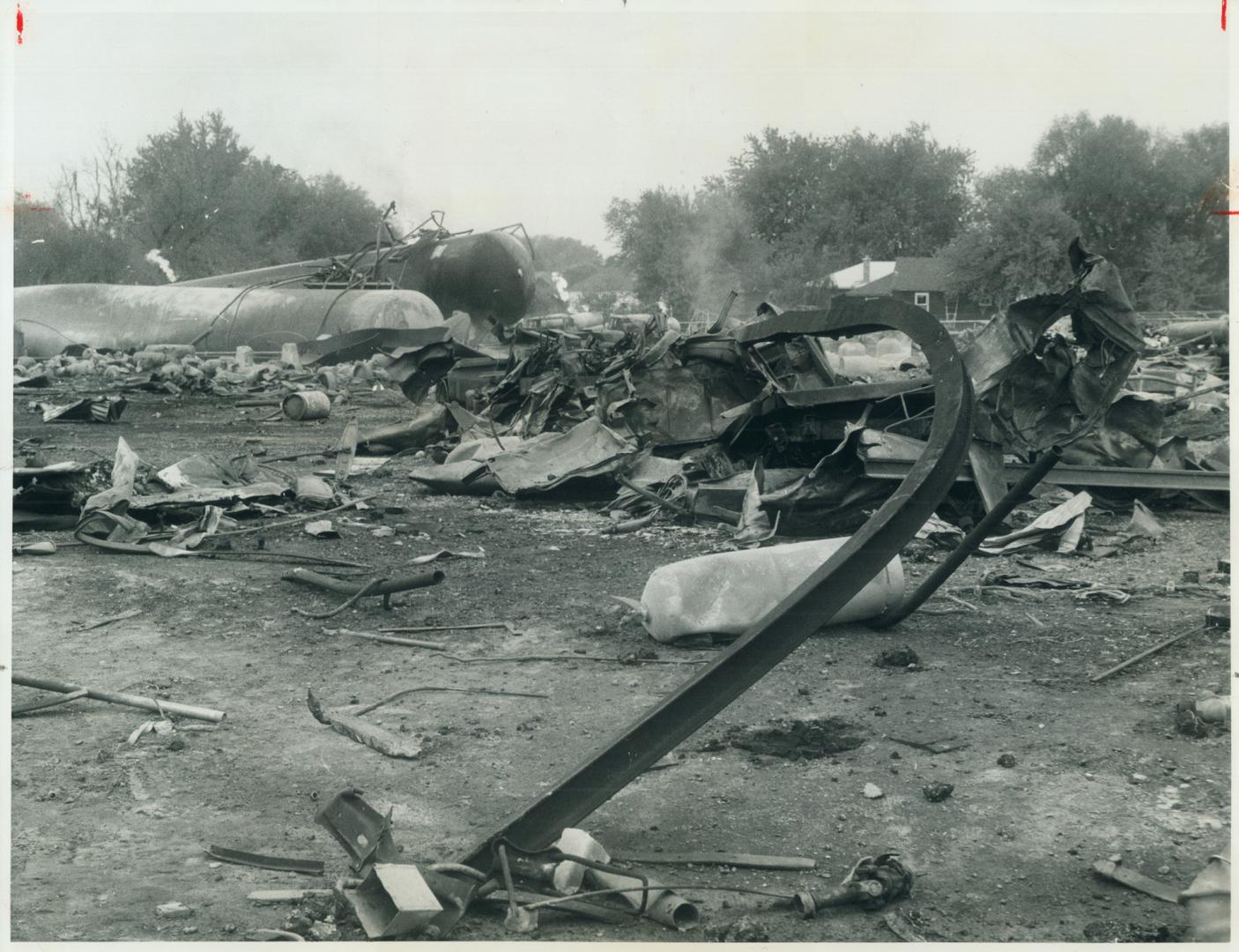 Twisted tracks at maple were left by propane explosions in night of terror, Tank in background, its flames now out, is where danger of new blasts are feared today and 26 more families were exacuated