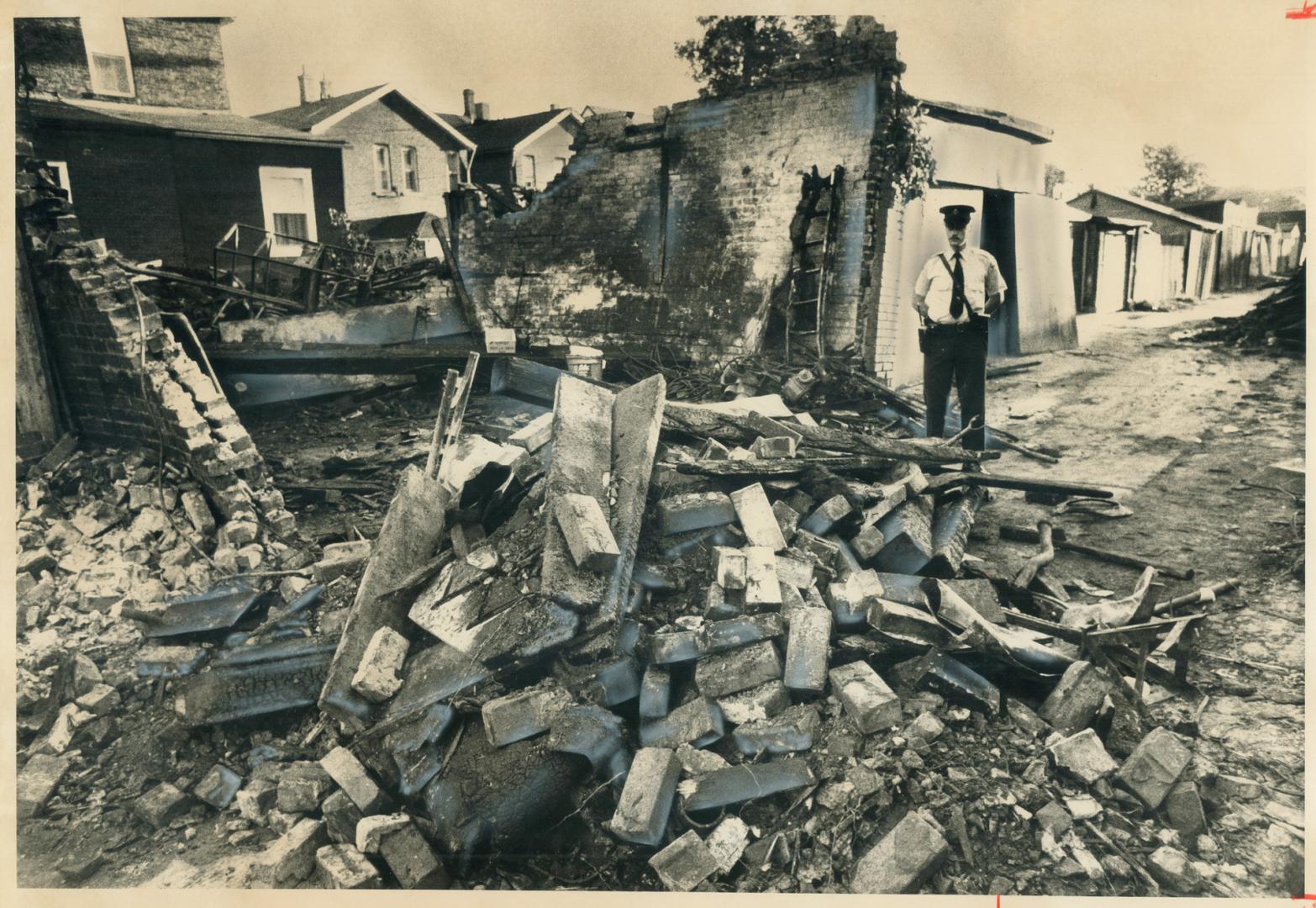 Double-Bricked walls tilted out by blast are all that remain after a tremendous explosion in a garage last night killed three men working inside. Cons(...)