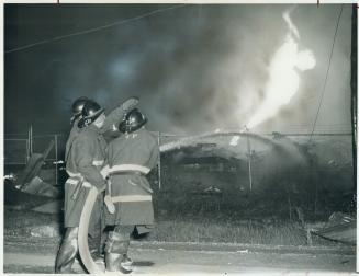 Firemen spray blazing storage yard during fire which could be seen for miles