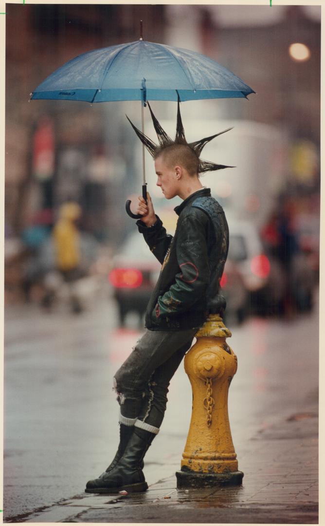 Chris Sweitzer of Toronto takes every-hair-in-place protection during yesterday's drizzle