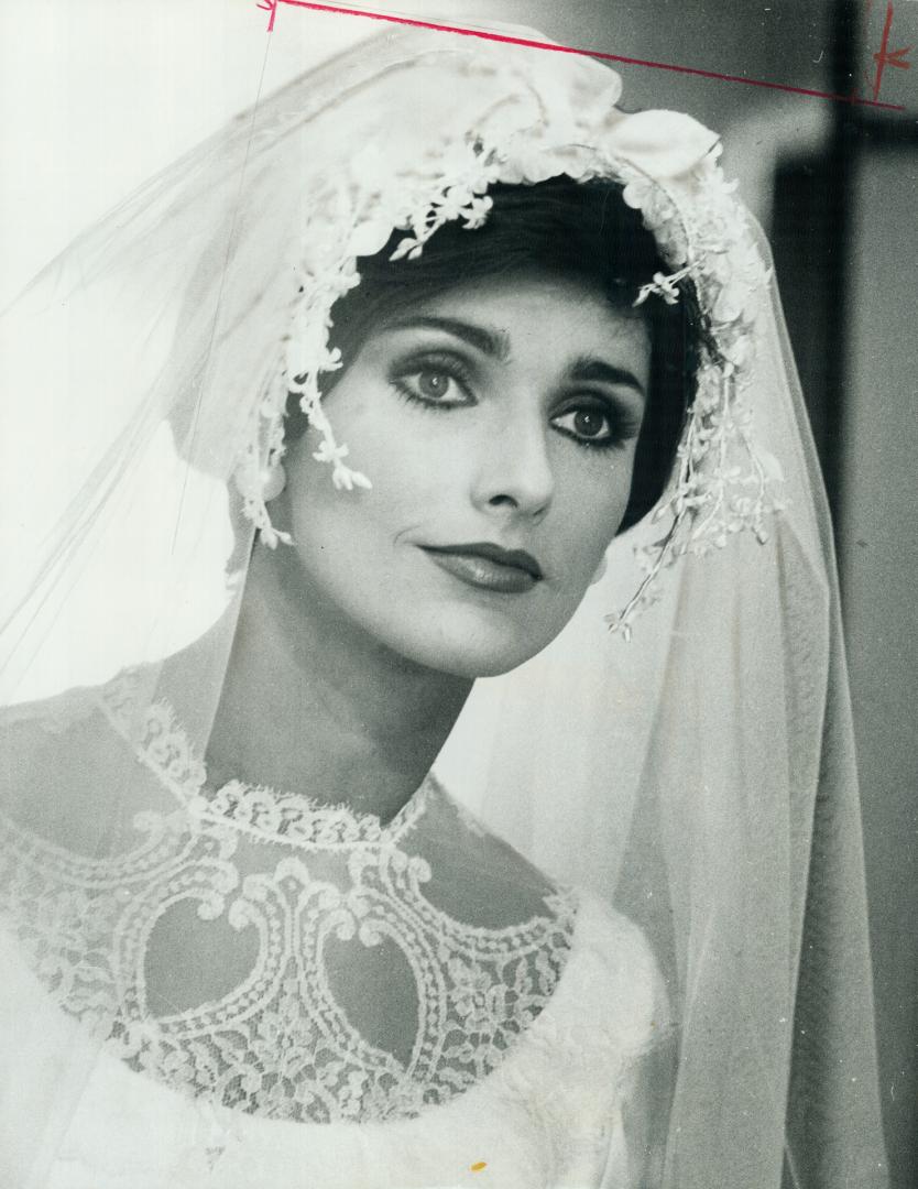 Traditional veil cascades from a face hugging headpiece of tiny flowers and leaves