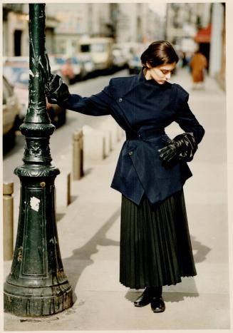 Yohji Yamamoto's Z-shaped belted jacket in navy blue gabardine and long, knife-pleated skirt is worn with his crushed leather gauntlet gloves