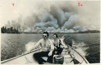 A 48,000-acre forest fire burning behind them, Star staff writer Alan Mettrick (front) and Natural Resources Department cameraman Ralph Campeau cross (...)