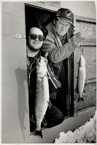 On ice: Danny Brunato of Thornhill, left, and Bill Linders of Bill's Fishing Huts at Virginia Beach Marina, peek out of their fishing hut door with a sample of the day's catch