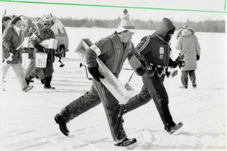 Fishermen Auger for good luck, A judge in striped vest sprints with canada's Dave Morton, above, to his choice of lucky hole in the ice while Finland'(...)