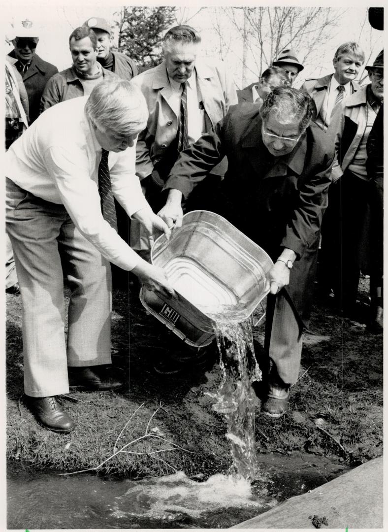 Lending a helping hand to nature, Brampton Mayor Ken Whillans, left, and Ontario's Natural Resources Minister Vince Kerrio tip Atlantic Salmon smoits (...)