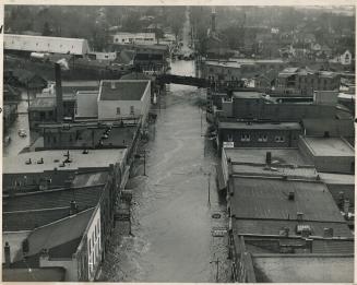 Main street through Brampton's business section is a roaring river as the Etobicoke races through the town