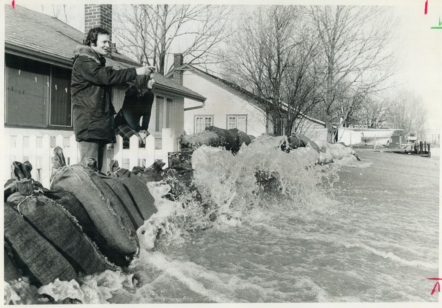 Behind Sandbags: Mr. and Mrs. Michael Hibbard watch Lake Ontario hit the Frenchman's Bay shoreline yesterday as sandbags protect their home