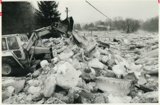 Work crews clear ice from roadways in Glen Williams near Georgetown after flood there Friday