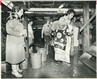 Harriet Reisler watches volunteers carrying soiled garments from dress shop after Port Hope flood