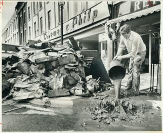 Town called Hope: One of Port Hope's hundreds of cleanup volunteers mans a bucket to bail mud and slush out of store basements in the town's flood ravaged business district