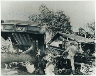 A volunteer fireman searches for flood victims under a tree on the banks of the Rapid Creek, west of Rapid City, S