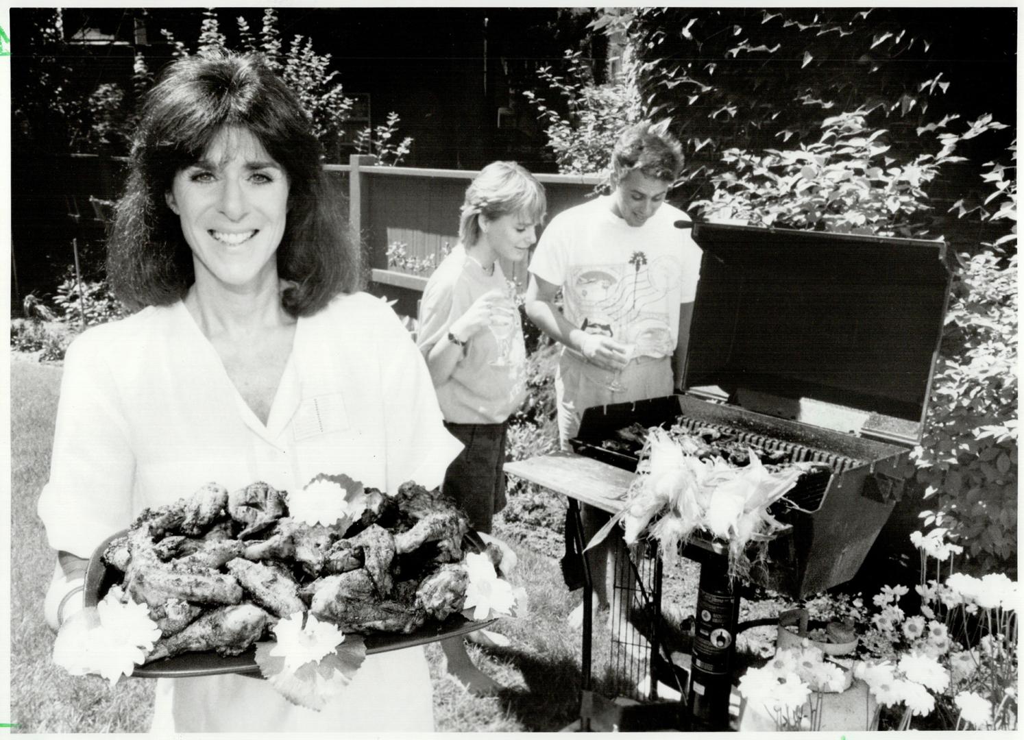 Family barbecue: Myra Sable displays her barbecued lemon chicken while her children, Kelly, 21, and Milton, 24, tend the barbecue