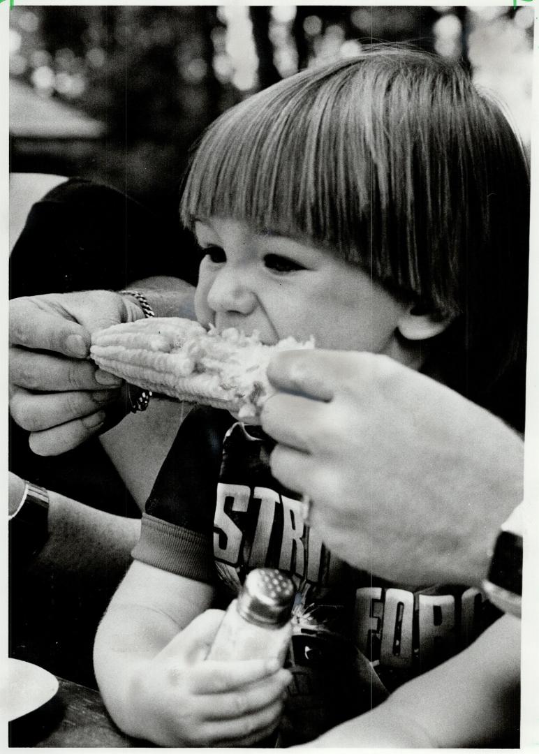 Yum, yum: Jeffrey Klein, 2, of Dundas, holds the salt while someone holds the cob of corn he's munching