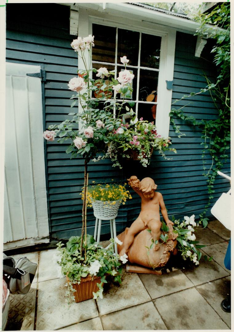 Standing Guard: Surrounding sculpture with baskets of ornamental flowers is one device used by Metro gardeners to convert tiny city yards into cozy nooks