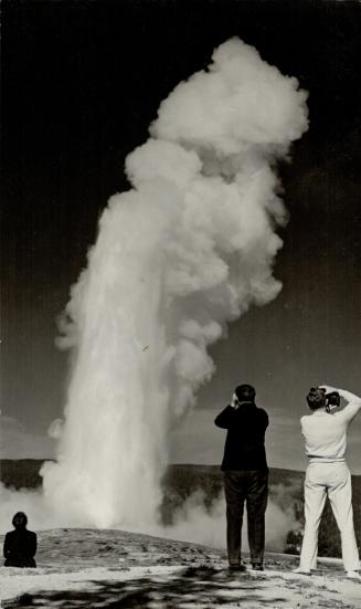 Old Faithful, Yellowstone Park's famous geyser, still retains its tourist appeal by conscientiously living up to the advertisement in the sign on the right