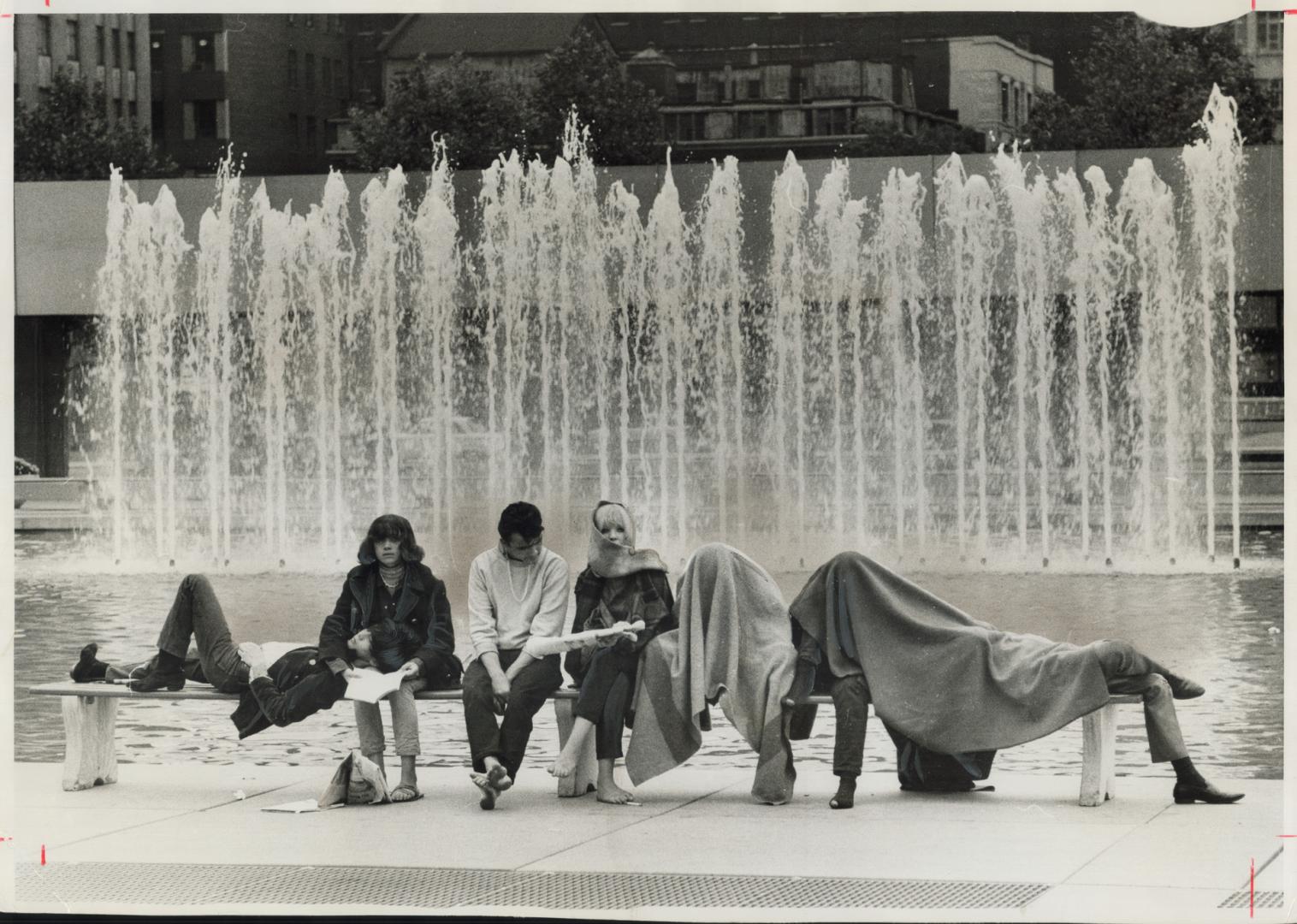 It was cool inside, too. Chilled hippies, whose planned starve-in at City Hall last night was dispersed by police, huddle under blankets beside founta(...)