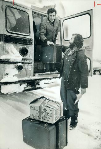 Jean Paquette of Montreal hands a bag to Albert Perron, 35, also of Montreal as they reach Matagami from the bush north of it, where they worked on $6(...)